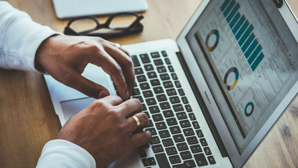 Closeup of a man's hands typing on a laptop displaying charts and diagrams, symbolizing strategic cannabis business turnaround planning.