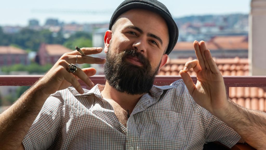  A smiling man enjoys a cannabis pre-roll while flashing the OK sign—symbolizing optimism and opportunity in the growing cannabis industry job market.