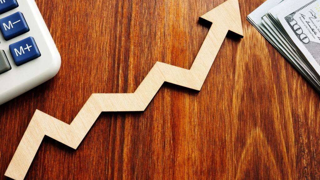 A calculator and upward arrow trendline on a desk symbolize how maximizing usable plant material enhances cannabis profitability and efficient cannabis cultivation practices.