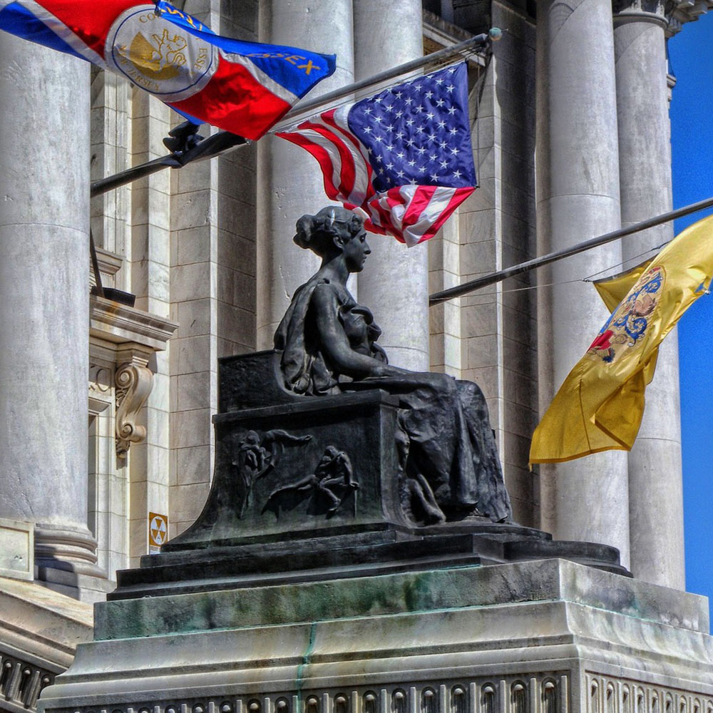 Statue of a woman sitting in a chair at Essex County Courthouse, symbolizing justice and the importance of navigating regulations in New Jersey.