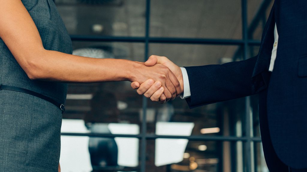 Two professionals shake hands after successfully securing a Minnesota cannabis license, highlighting the benefits of expert Minnesota cannabis consulting.
