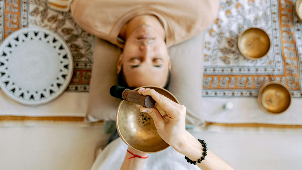 A patient lies down peacefully while a facilitator uses sound waves to promote relaxation, creating a supportive environment for psilocybin-assisted therapy.