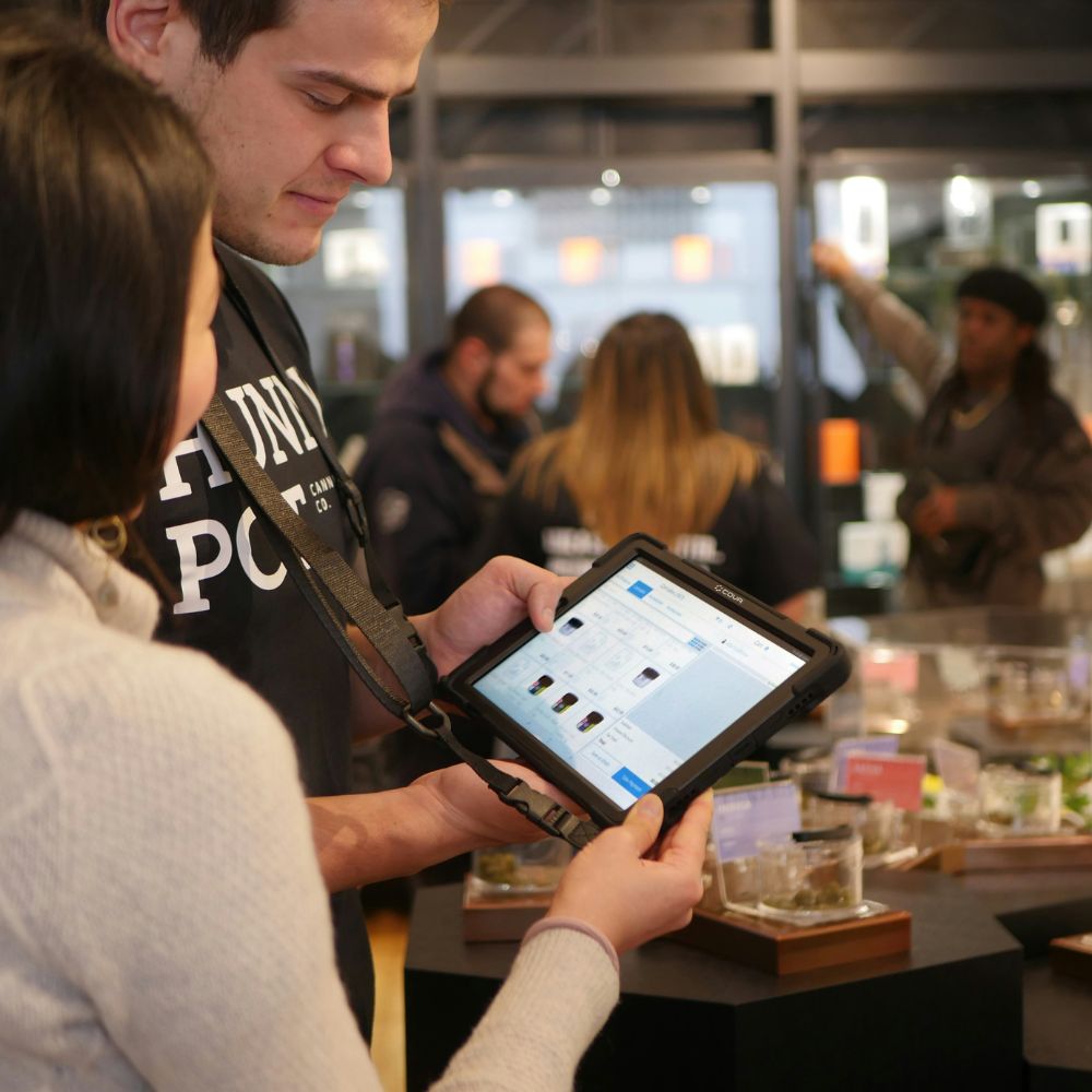 Budtender using tablet POS system to display cannabis products to a customer