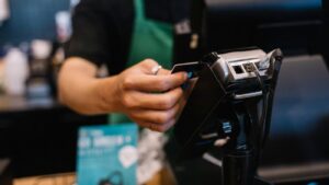 Budtender processing a customer payment through a cannabis POS system, ensuring accurate seed-to-sale tracking, dispensary inventory management, and compliance reporting automation that enforces cannabis purchase limits.
