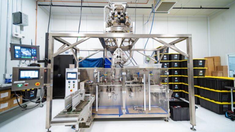 Modern stainless steel automated cannabis pre-roll processing machine in a dedicated production room.