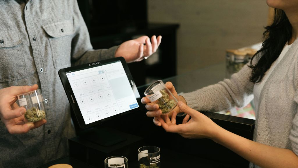 A budtender consulting with a customer inside a cannabis dispensary, representing the retail microbusiness license path.
