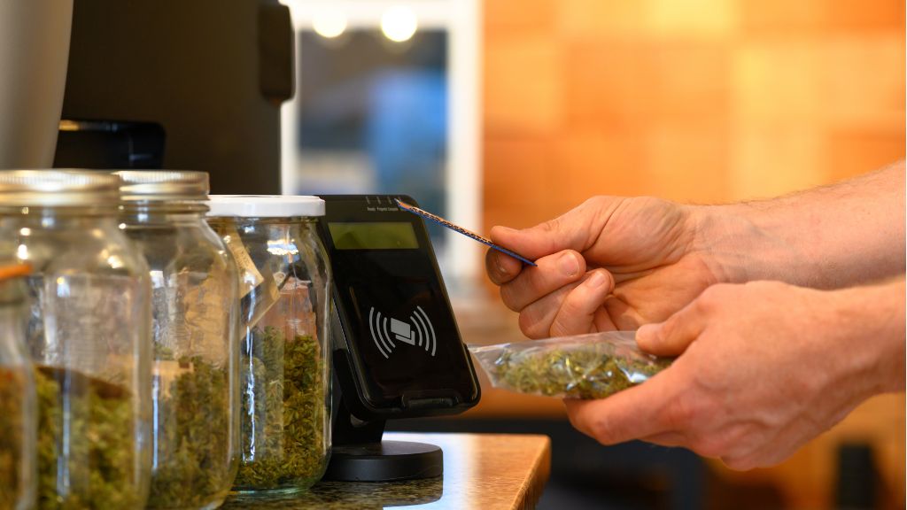 A budtender using a payment processor to check out a customer's order at a cannabis dispensary.