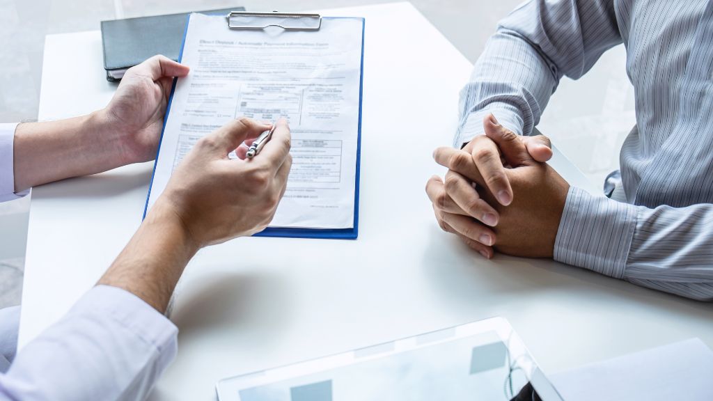 A Catalyst BC cannabis consultant reviewing Virginia cannabis equity and loan fund information with a client at a desk.